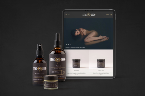 Two body oil bottles and a lip balm next to an iPad to show the brand identity and website design for stag+seer brand.